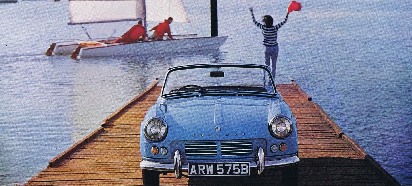 blue car on dock, woman waving at sailboat